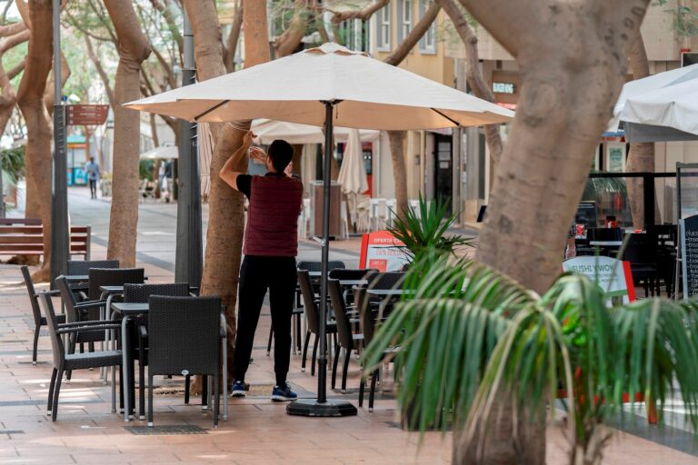 Un camarero coloca una sombrilla en la terraza de un bar en la calle Betenchourt Alfonso de Santa Cruz de Tenerife.